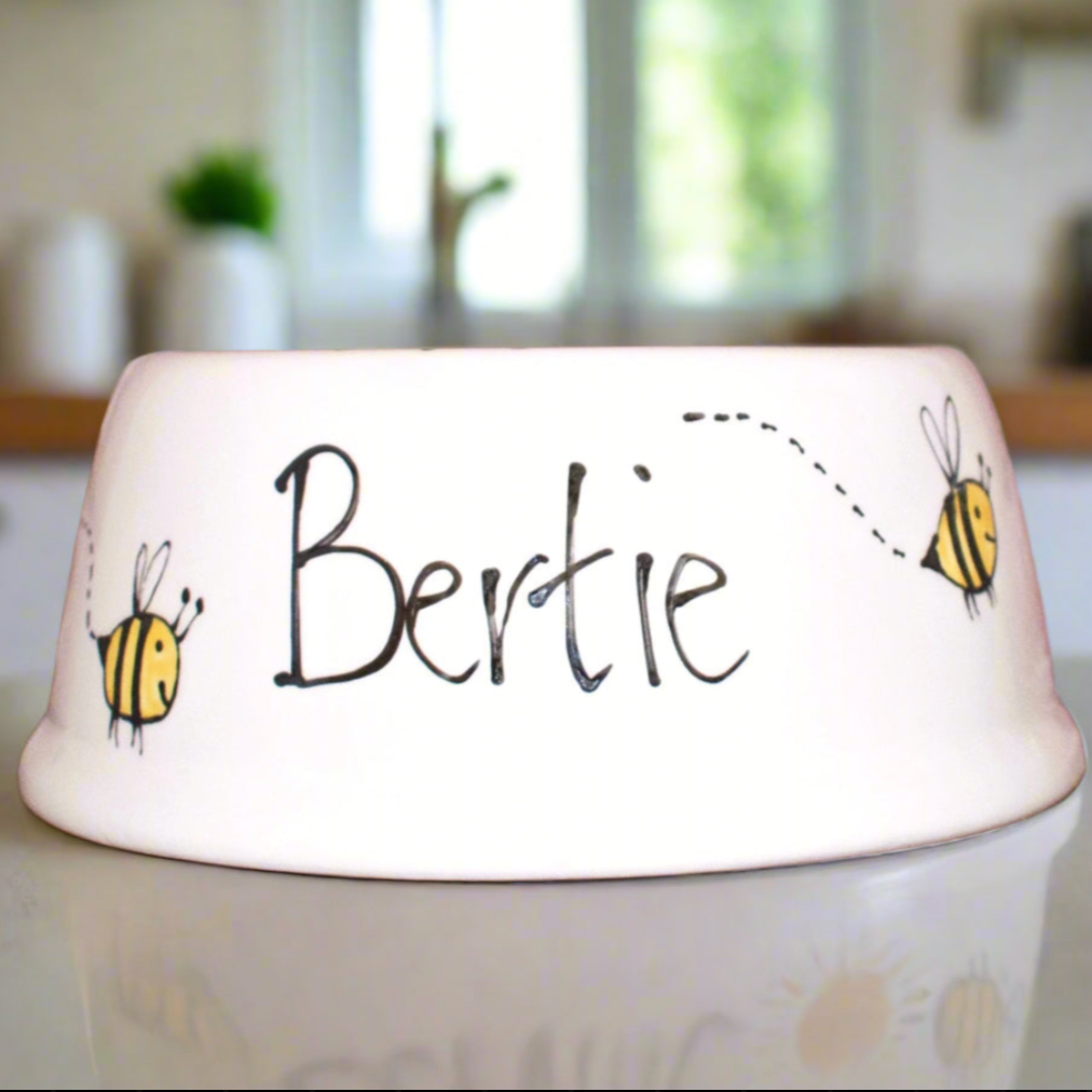 White pet bowl with 'Bertie' and bee designs on a kitchen counter.