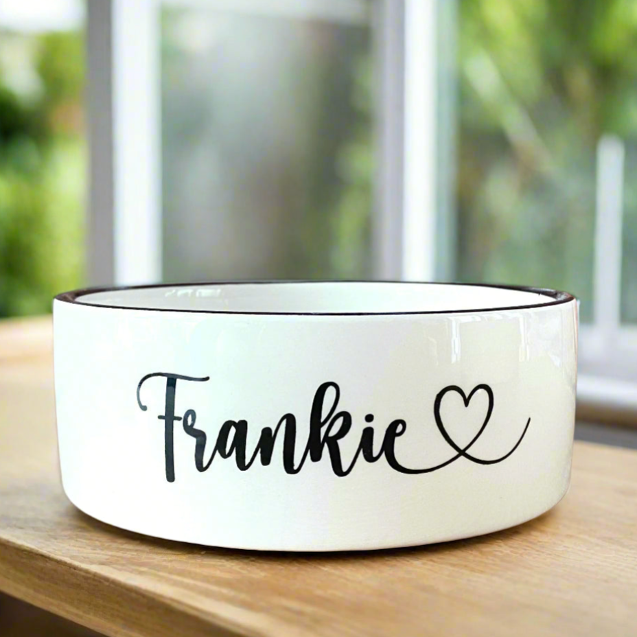 White pet bowl with 'Frankie' and a heart on a wooden table